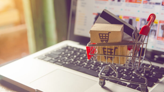 Shopping online concept - Parcel or Paper cartons with a shopping cart logo in a trolley on a laptop keyboard. Shopping service on The online web. with payment by credit card and offers home delivery.